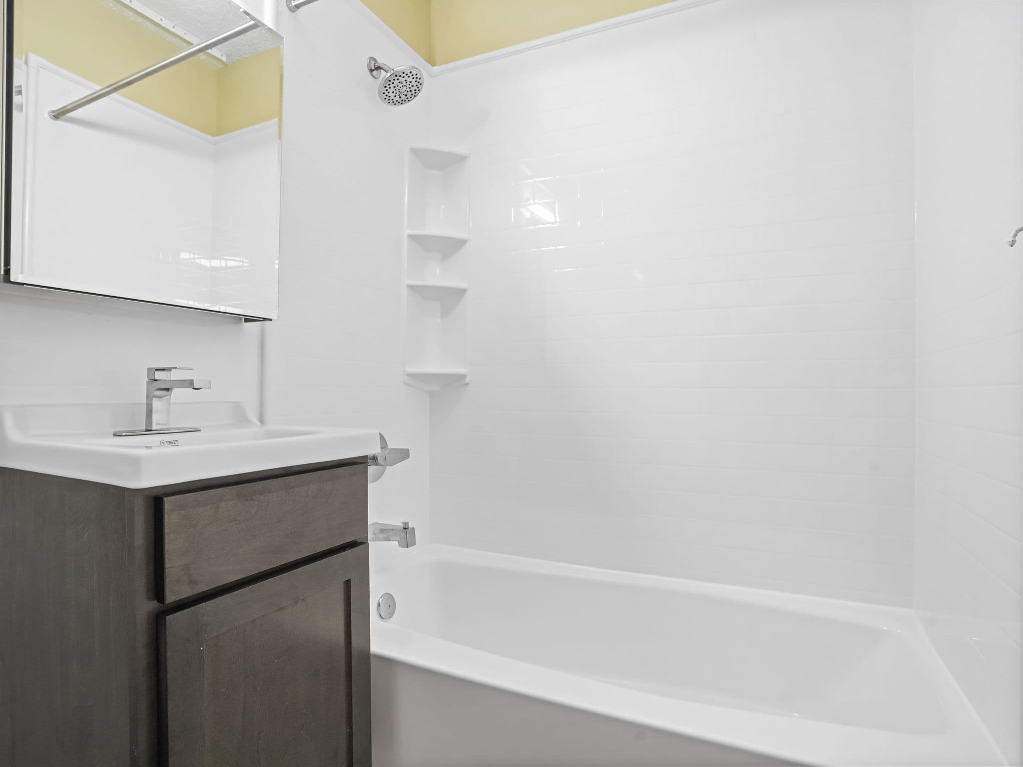 Completed Tindel bathroom with a seamless white wall system, tub and vanity